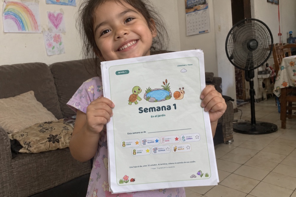 Una niña muestra orgullosa su Semana 1 engrapada, con las estrellas coloreadas