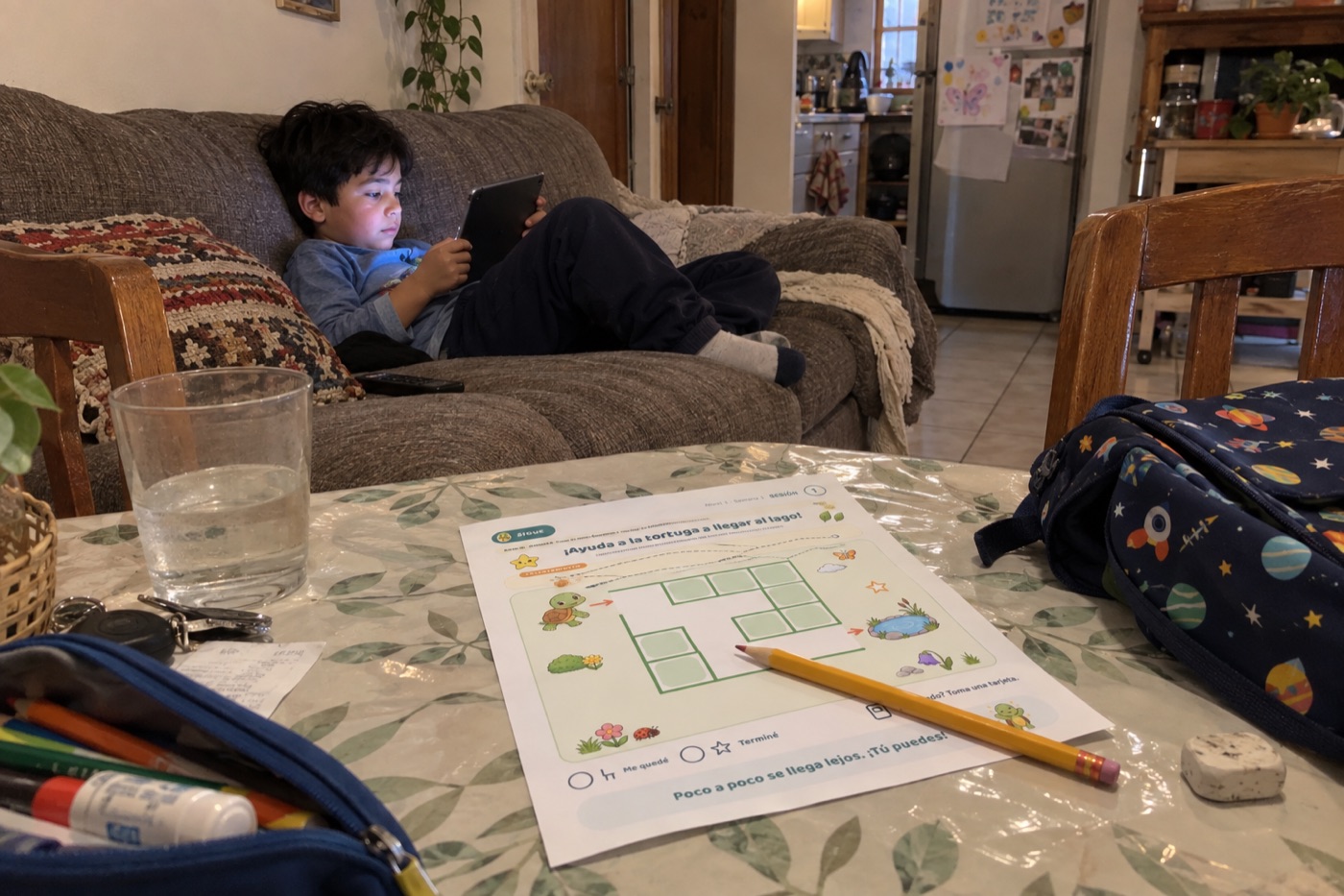 Un niño con la tablet mientras su hoja espera en la mesa